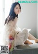 A woman in a white dress sitting on a window sill.