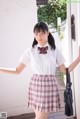 A woman in a white shirt and plaid skirt posing for a picture.