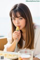A woman sitting at a table eating a piece of food.