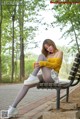 A woman sitting on a bench in a park.