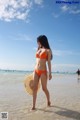 A woman in an orange bikini standing in the water.