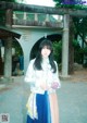 A woman standing in front of a wooden gate.