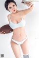 A woman in a blue bikini holding a football and taking a selfie.