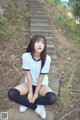 A woman sitting on a set of stairs in the woods.