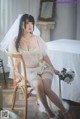 A woman in a wedding dress sitting on a chair.