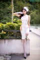 A woman in a white dress sitting on a ledge.