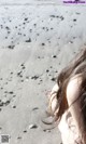 A woman with her hair blowing in the wind on a beach.